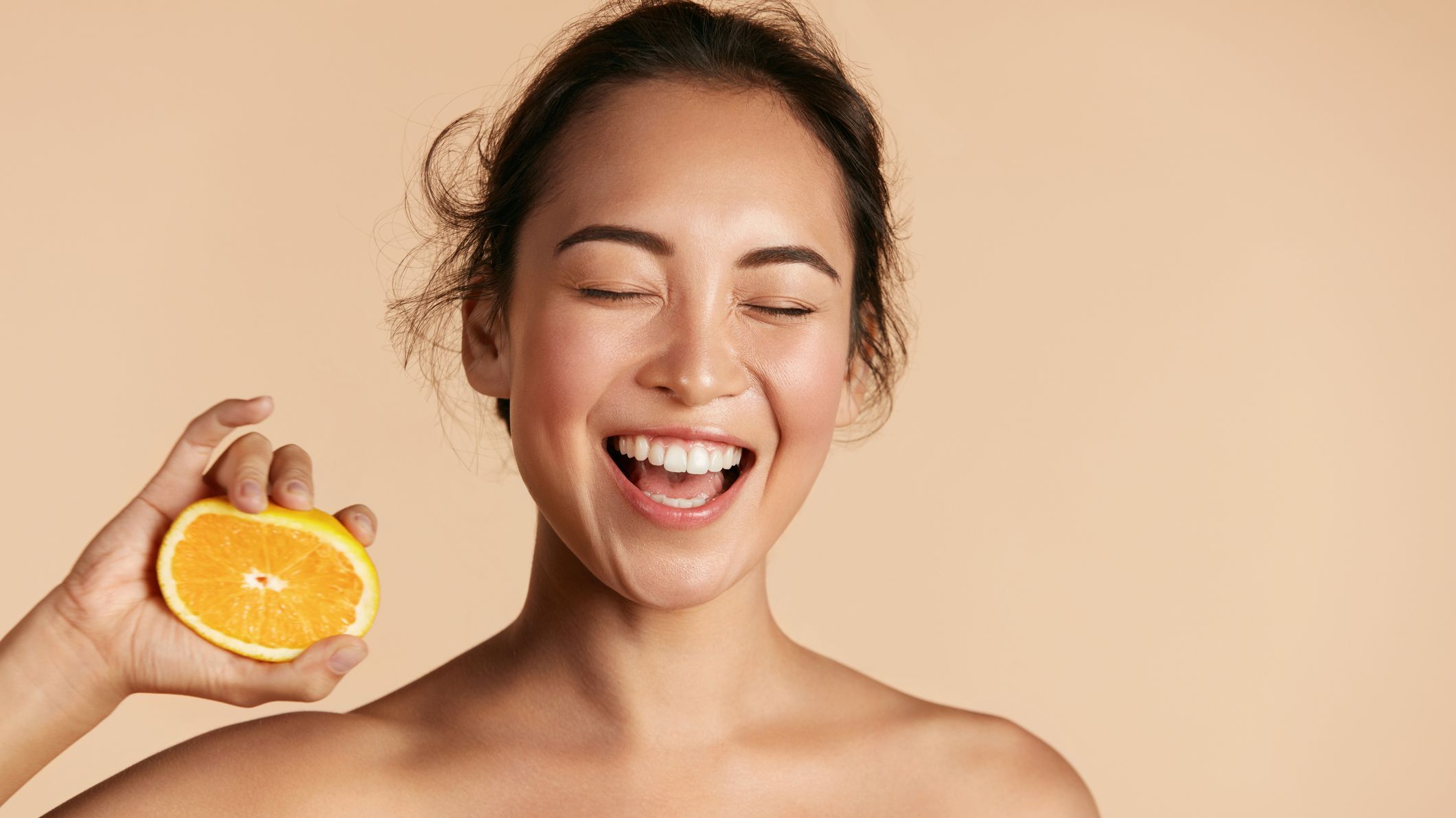 Smiling woman posing and holding an orange