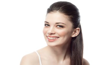 smiling young woman with long dark hair tied tied in a ponytail