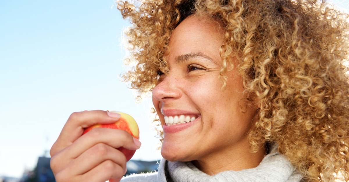 Close up side portrait of healthy young african american woman holding apple