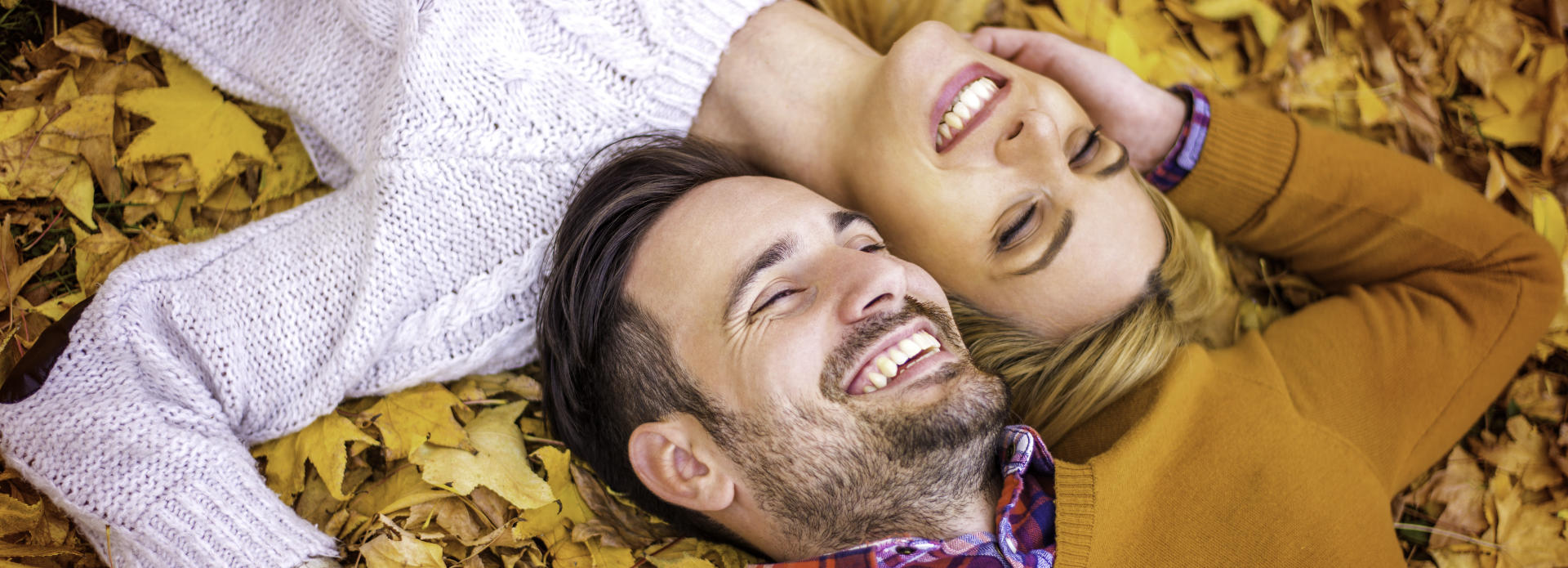 happy couple lie on autumn leaves