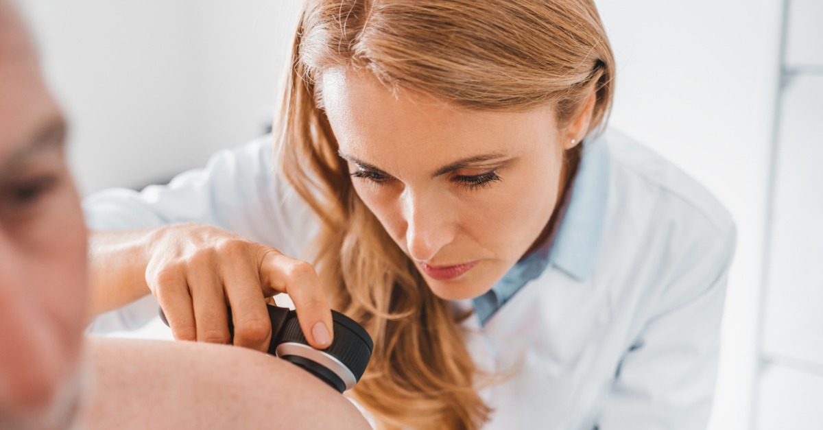 Female dermatologist performing a skin cancer screening using a dermatoscope