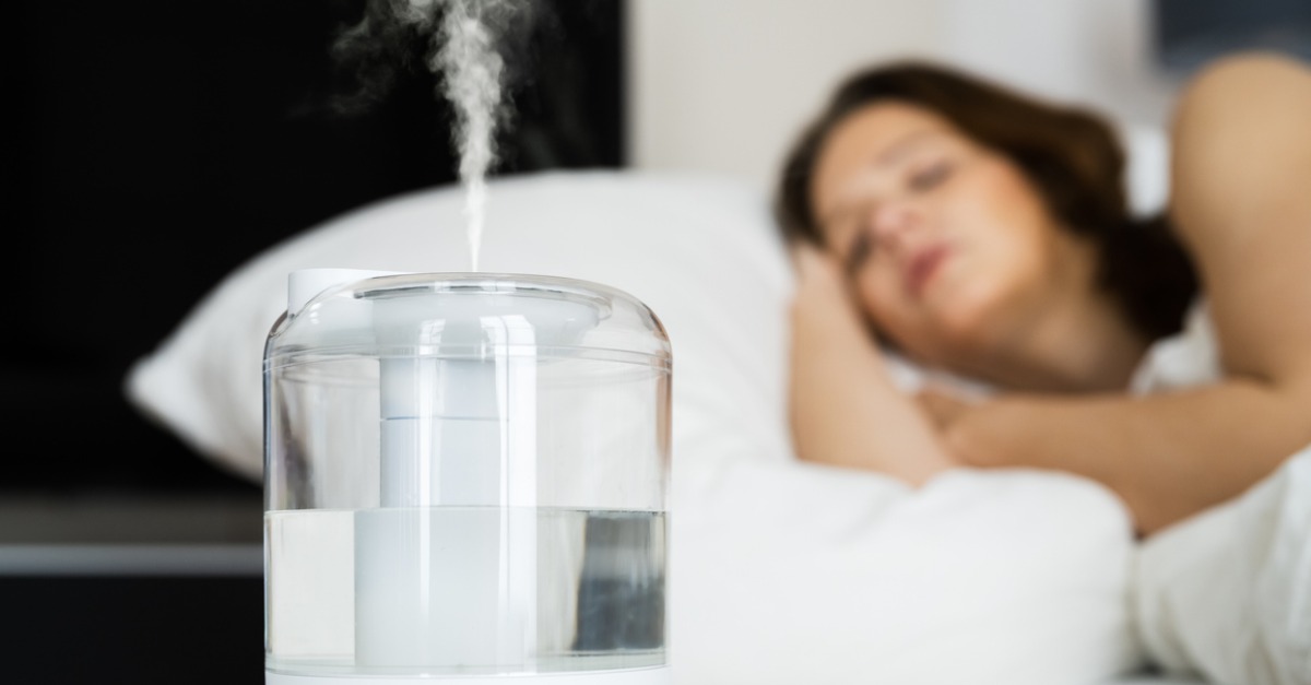 A lady sleeping in bed while a humidifier is running.