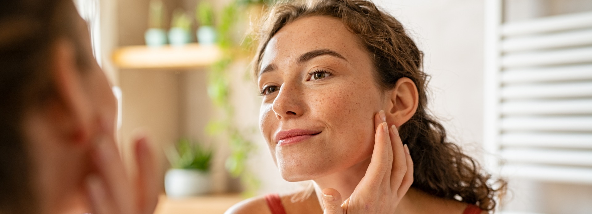 close-up of young woman inspecting acne scars in the mirror