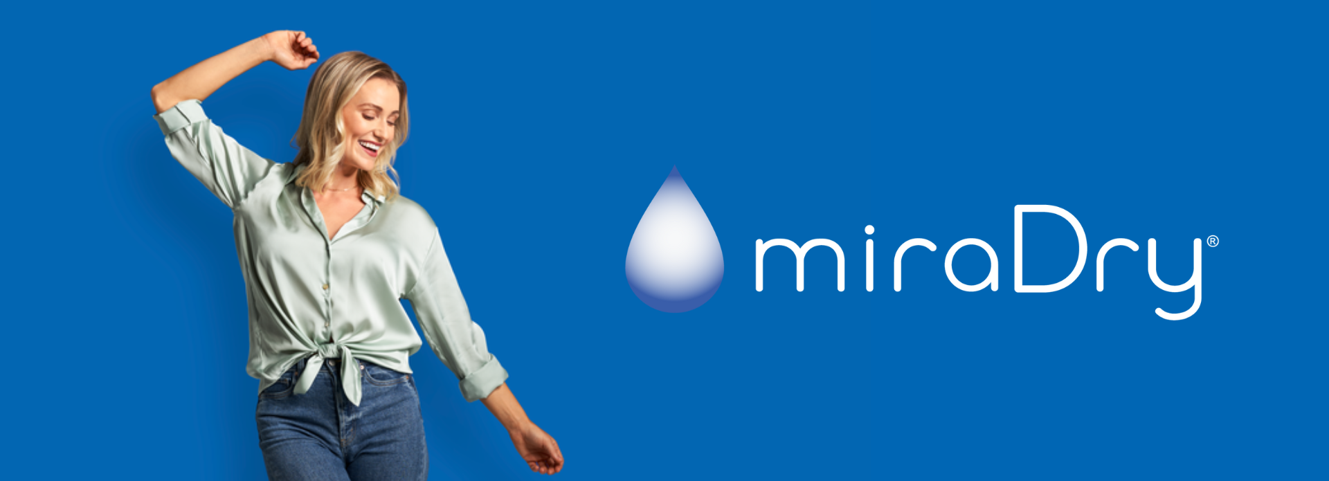 Woman posing with her arm raised in front of a blue background with a white miraDry logo.