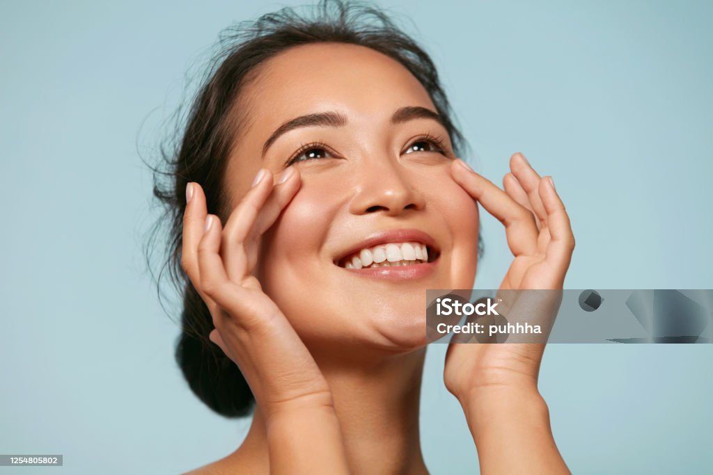 Lady touching clear skin on her face.